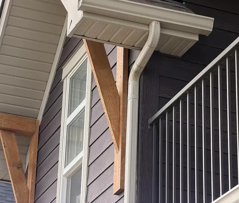 New gutters and downspouts installed along a roof line.